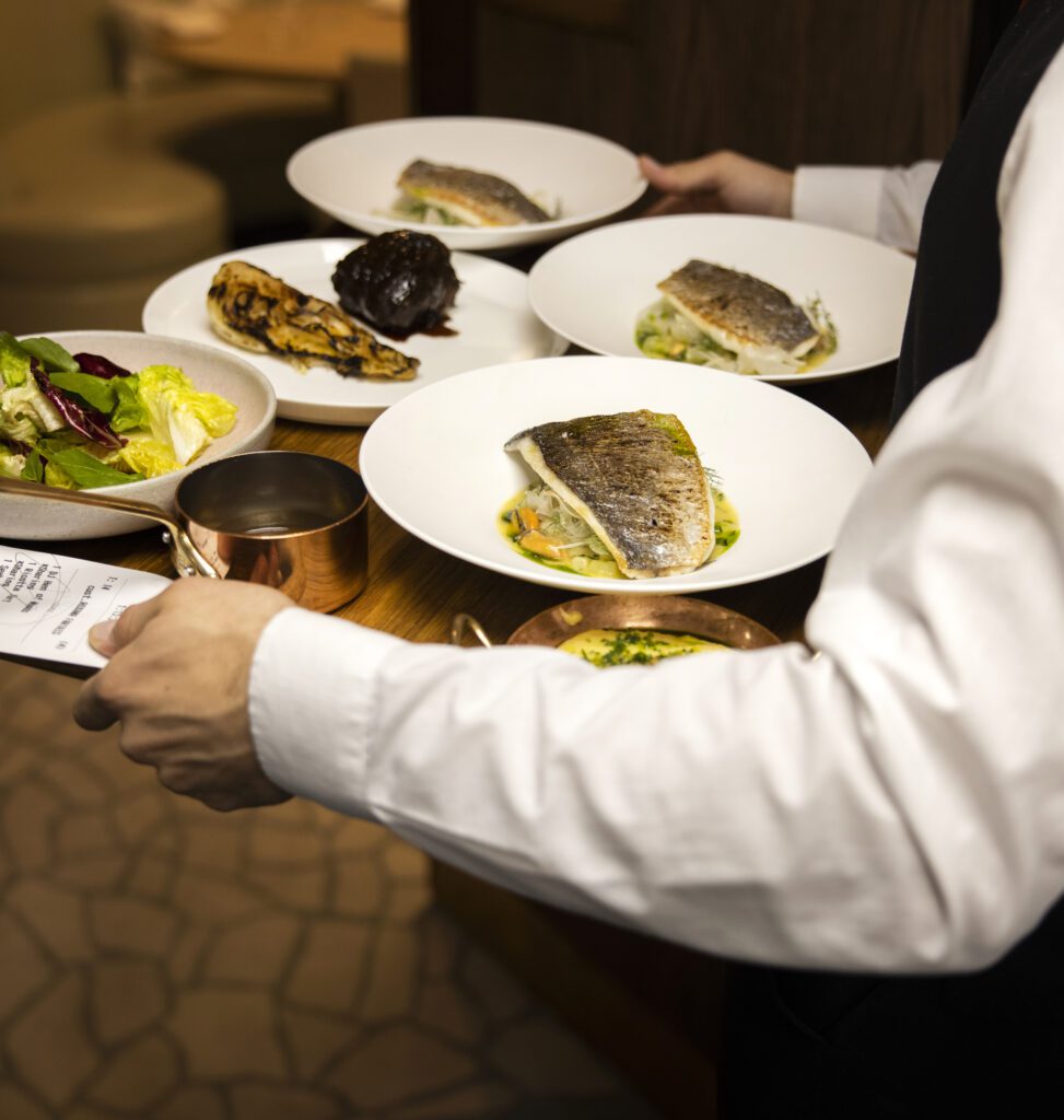 Waiter is carrying dishes on a tray at Murano