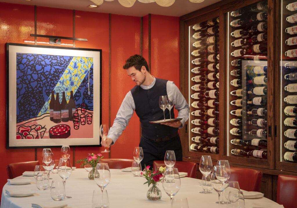 Waiter is setting the table in the private dining room at Murano