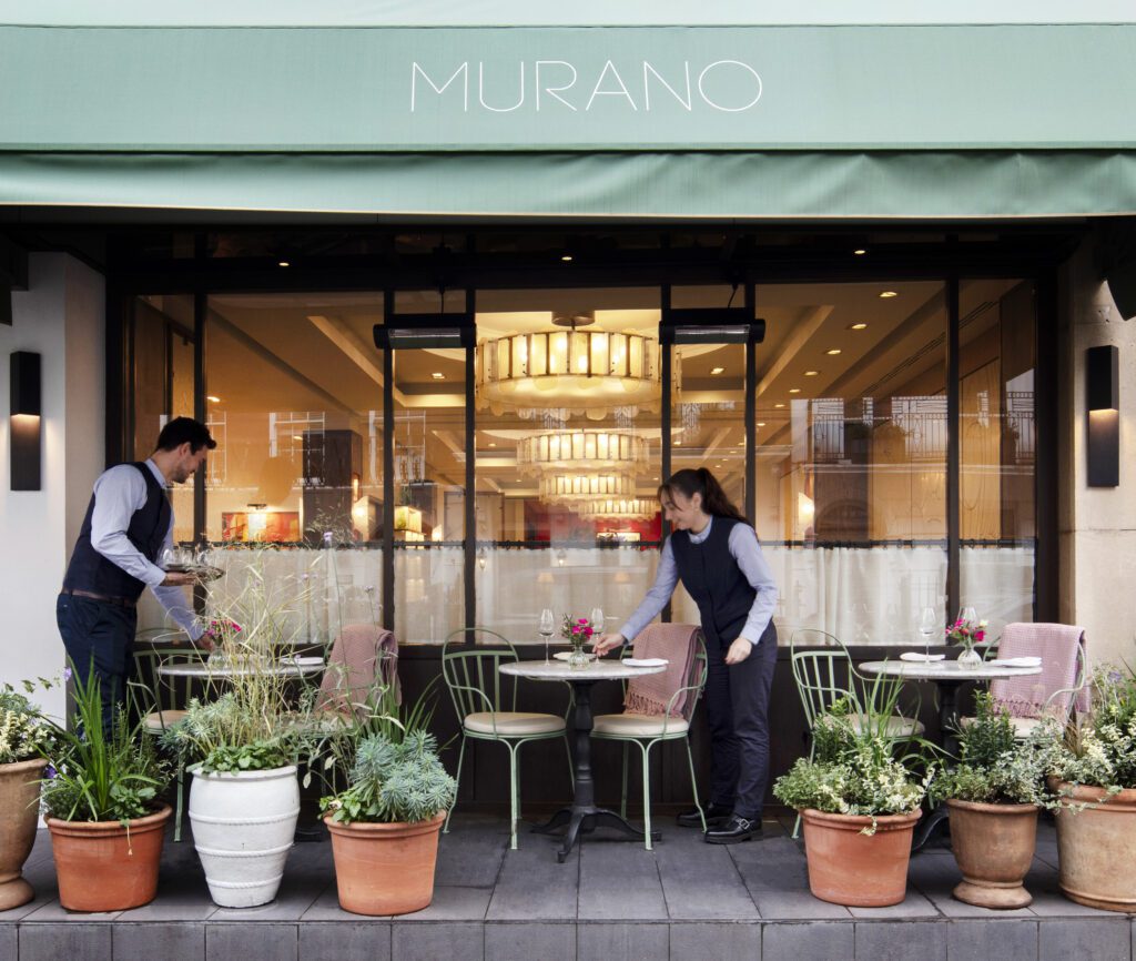 Waiters are setting the tables on the terrace at Murano